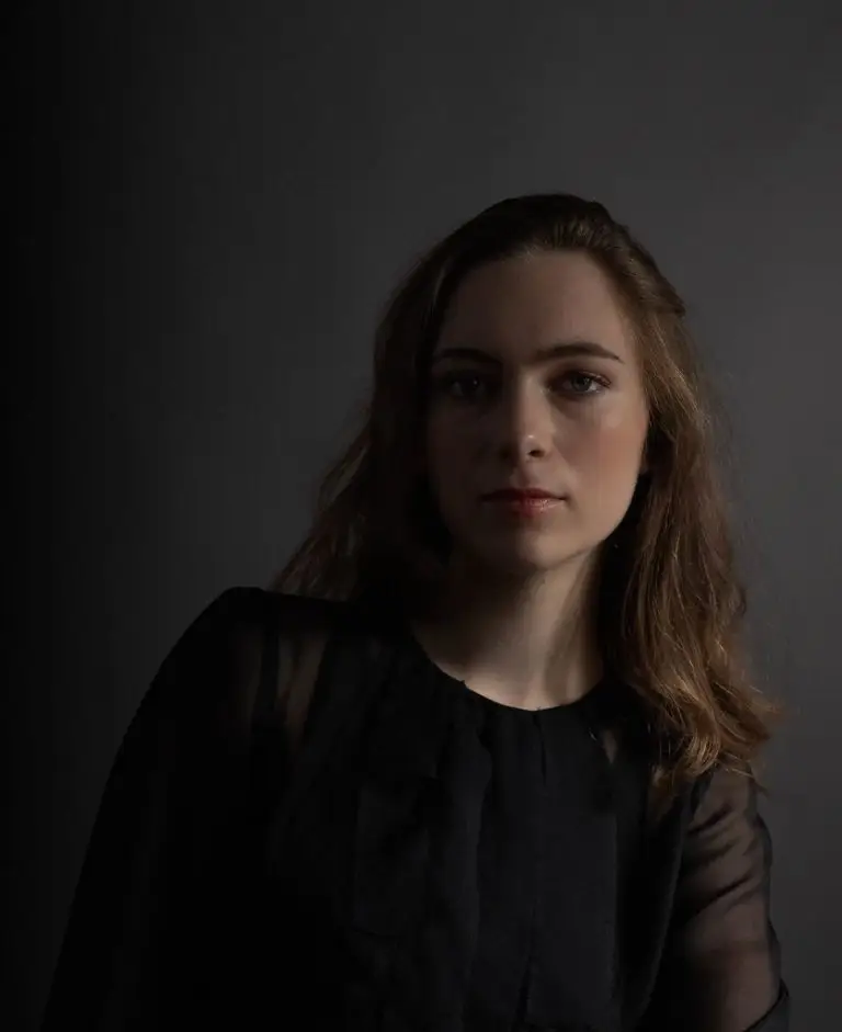Close-up of model wearing black silk chiffon couture blouse with slim sleeves, small cuffs and flowing panels, by Saskia ter Welle