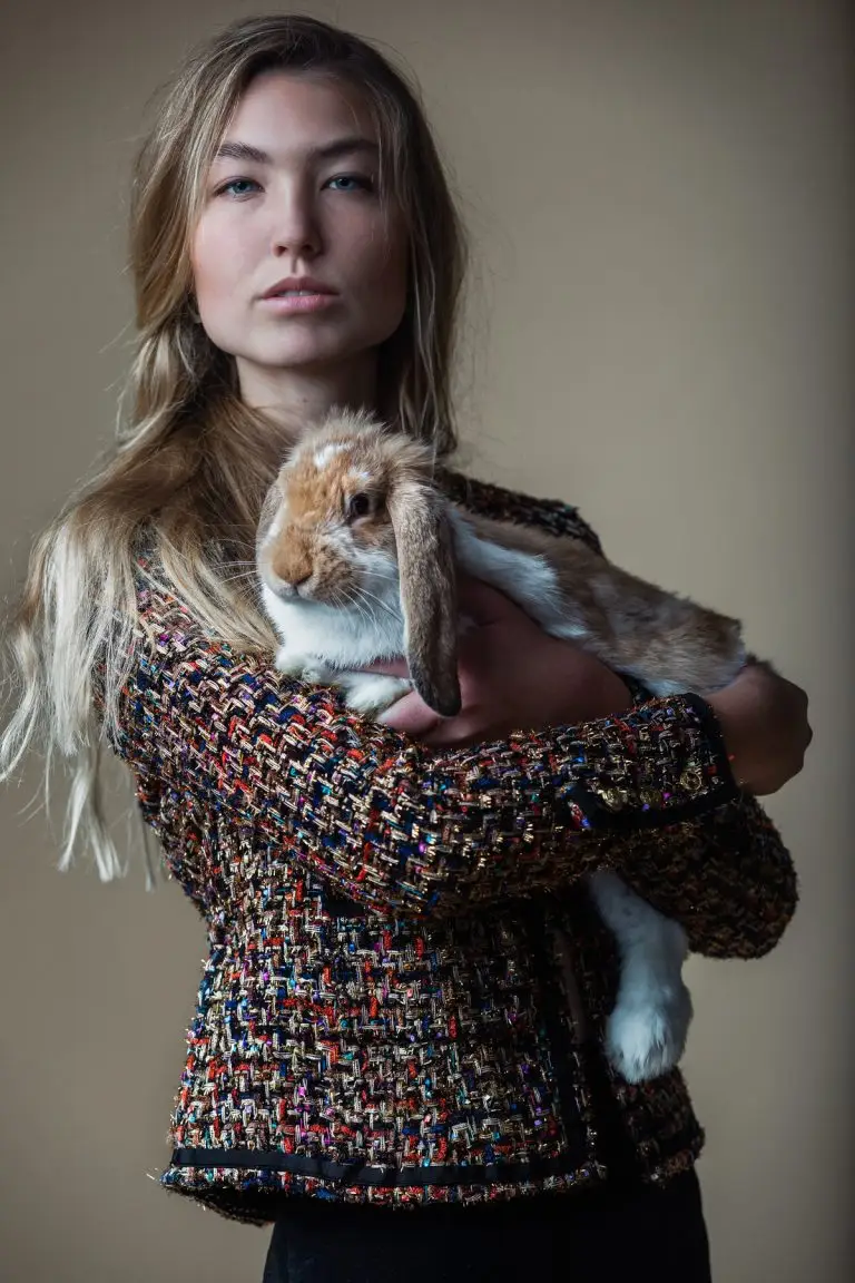 Model holding a rabbit while wearing a French-inspired couture jacket in multicoloured tweed with golden accents, by Saskia ter Welle