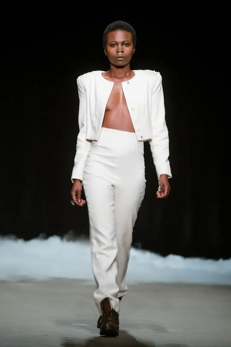 White couture trouser suit with high-waisted trousers and short tailored jacket featuring richly embroidered epaulettes, by Saskia ter Welle For Amsterdam Fashion Week