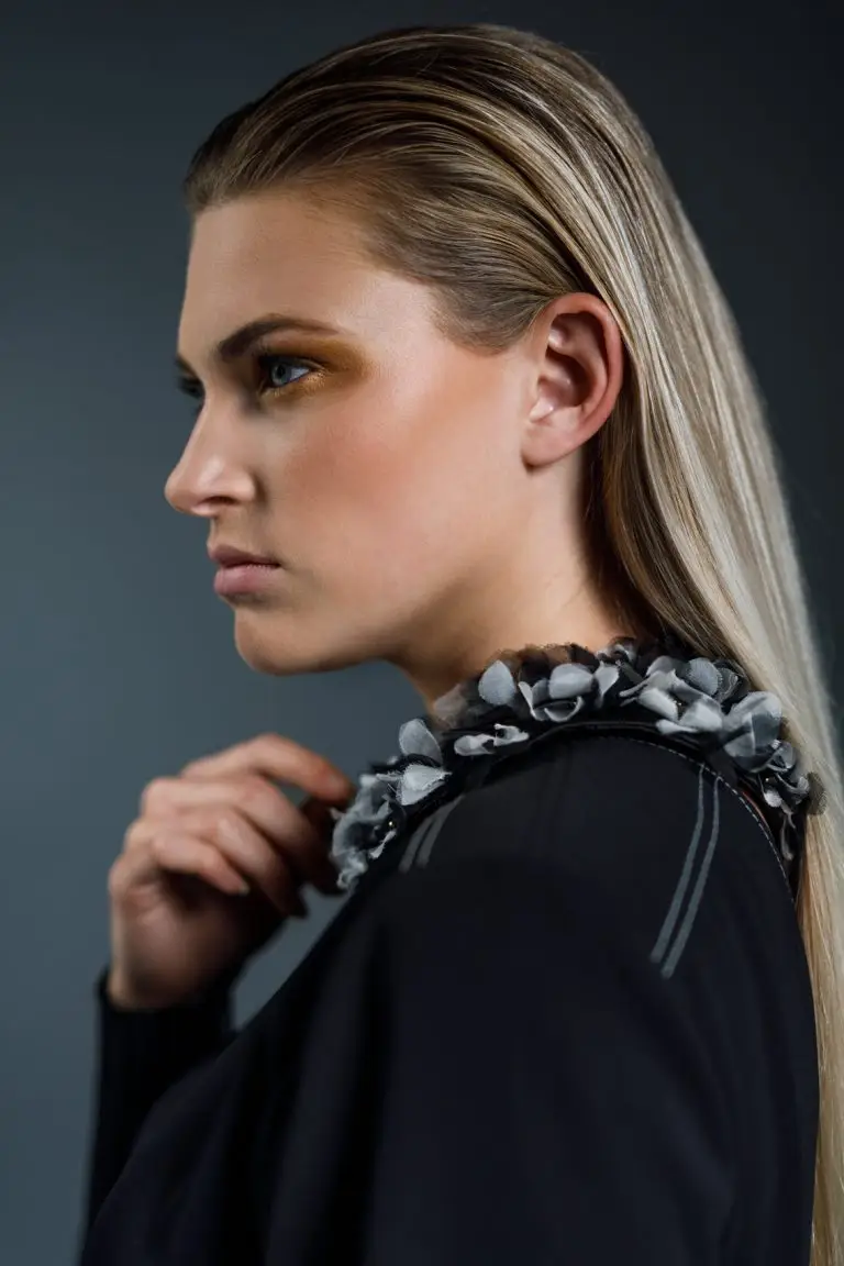 Side view of model Rianne wearing embroidered couture collar in black and ecru with silk organza flowers and golden accents, by Saskia ter Welle