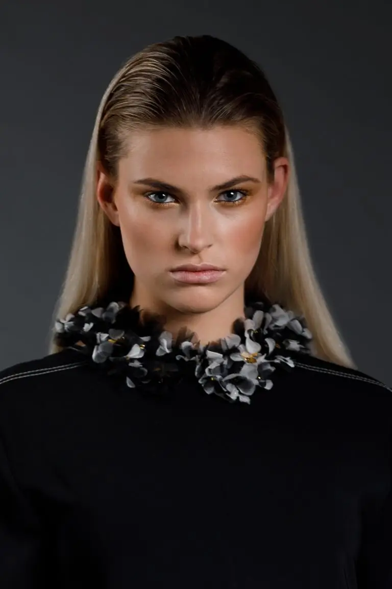 Close-up front view of model Rianne wearing embroidered couture collar in black and ecru with silk organza flowers and golden accents, by Saskia ter Welle