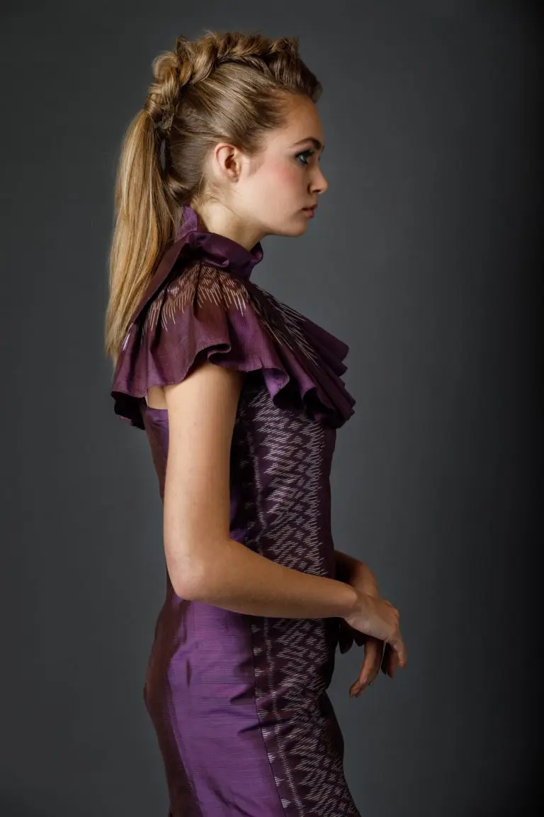 Side view of purple Thai silk couture cocktail dress with pleated collar, detachable bow and knee-length straight skirt with slit, by Saskia ter Welle