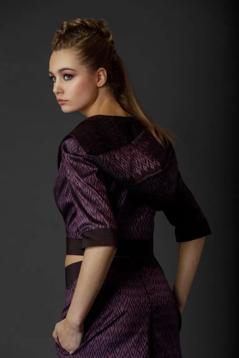 Back view of purple Thai silk couture suit with woven pattern, showing hooded short jacket and cropped wide-leg trousers, by Saskia ter Welle