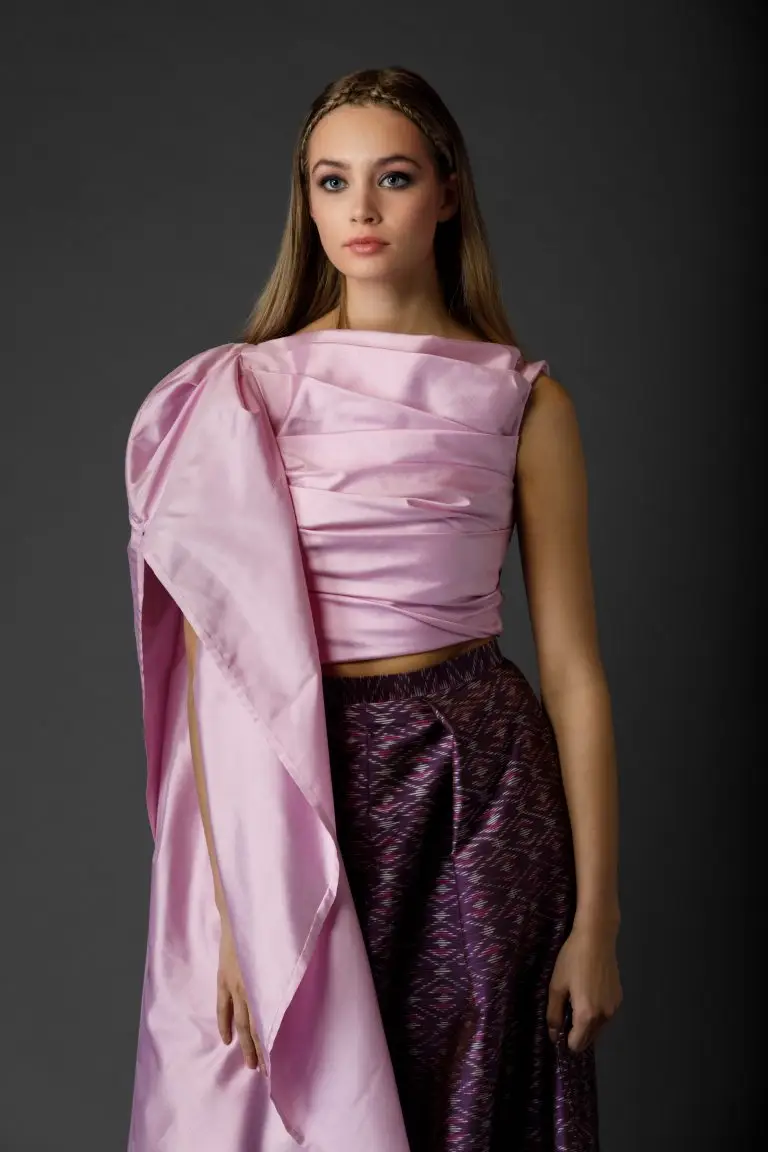 Model wearing patterned purple long couture skirt with sculpted light pink corset top featuring one sleeveless side and one dramatic sleeve, by Saskia ter Wel