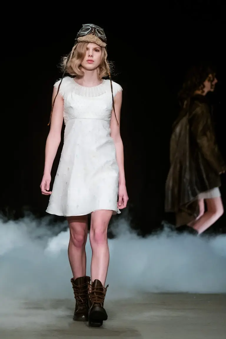 Opening look at Amsterdam Fashion Week: short white couture dress with all-over pearl embroidery, pearl-accented neckline and feathers, by Saskia ter Welle